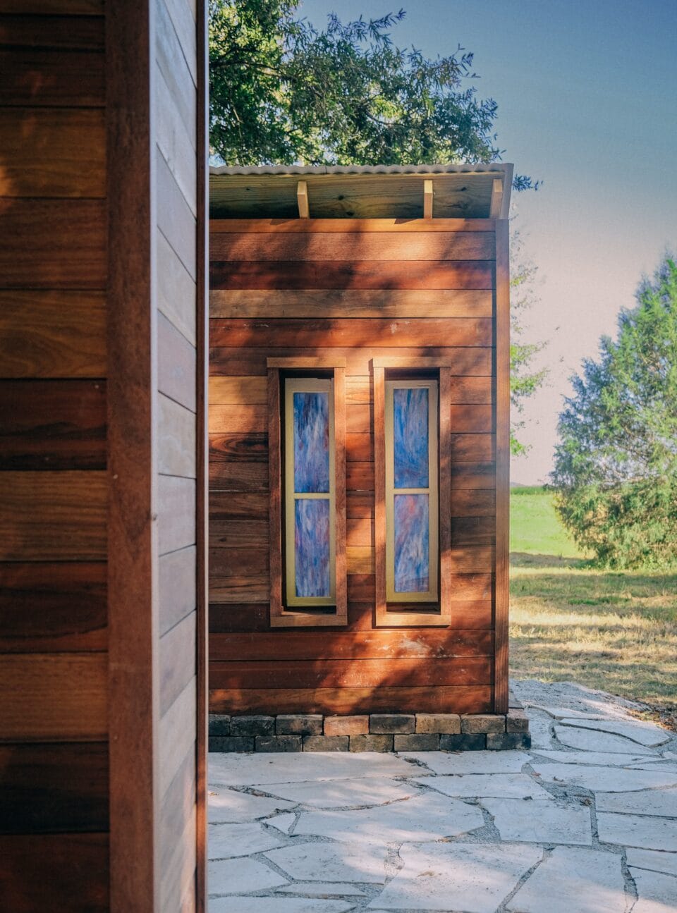 a wooden structure with two stained glass windows peeks out from behind another wooden structure