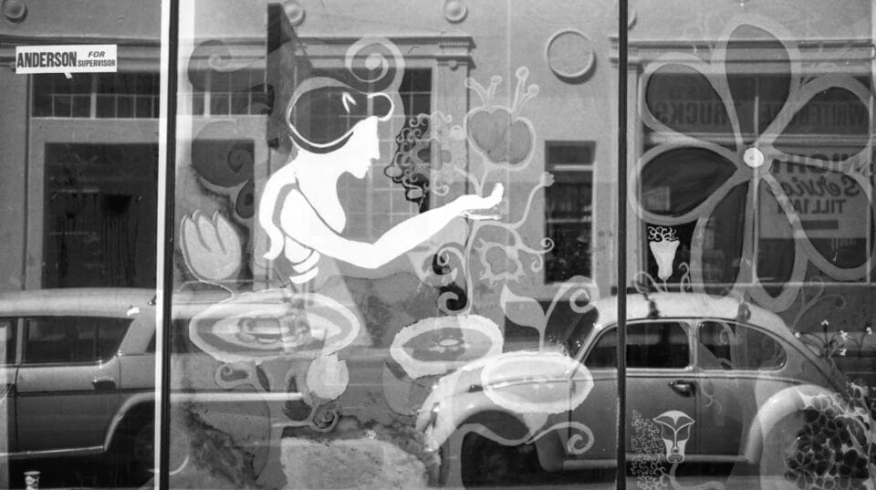 a black and white image of a store window with the photographer's faint reflection